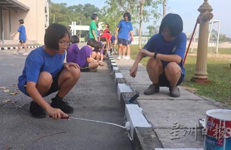 学生齐心协力油漆校园的人行道。