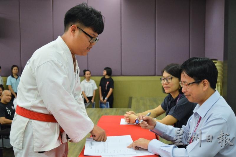 跆拳道新任主席正在等待校长签署宣誓书。