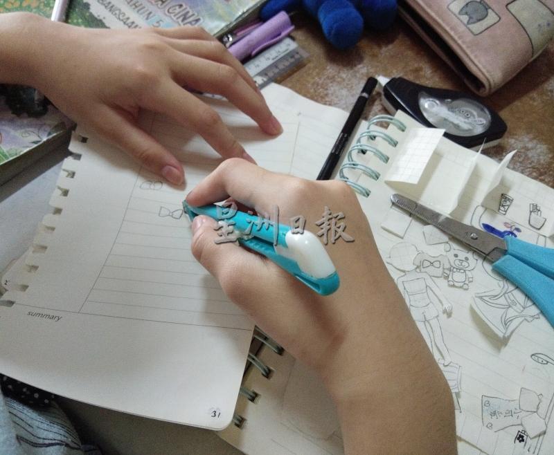 郭泫孜在旧纸张上画上图案，并切割下来制作小手工。