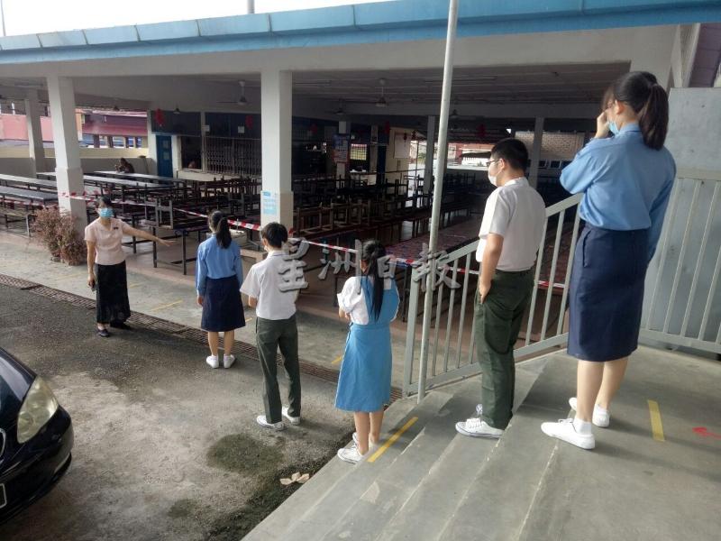 学生在老师的监督下，循规蹈矩地准备到食堂购买午餐。