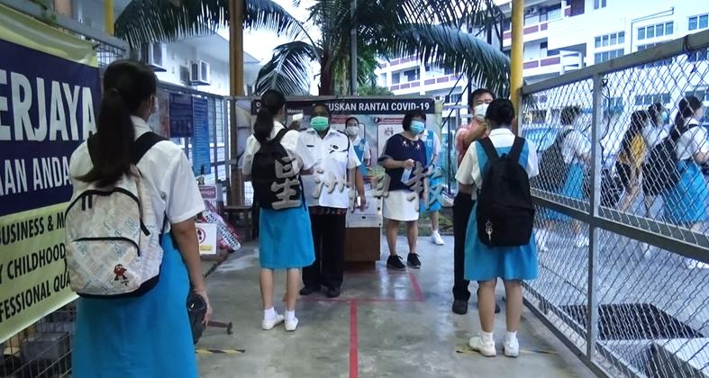 学生在学校门口检测体温及消毒双手。