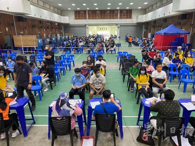 学生在家长陪同下，排队登记与接种疫苗。