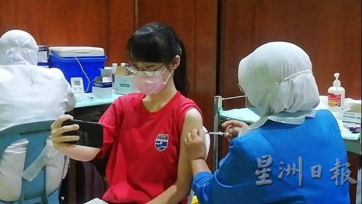 学生记录打疫苗过程留念。
