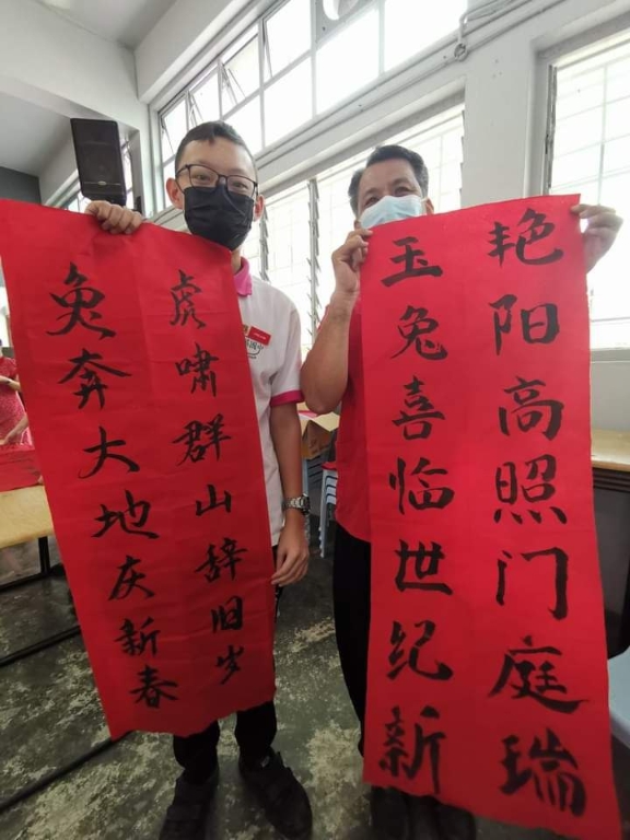 华文老师张明辉（右起）与初中组冠军林继铵手握自己的作品合照。