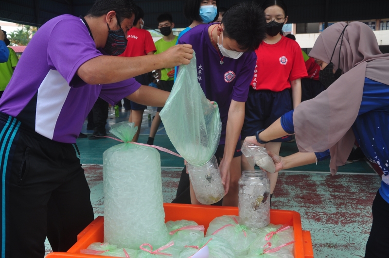 老师帮助学生将冰块倒入容器中。