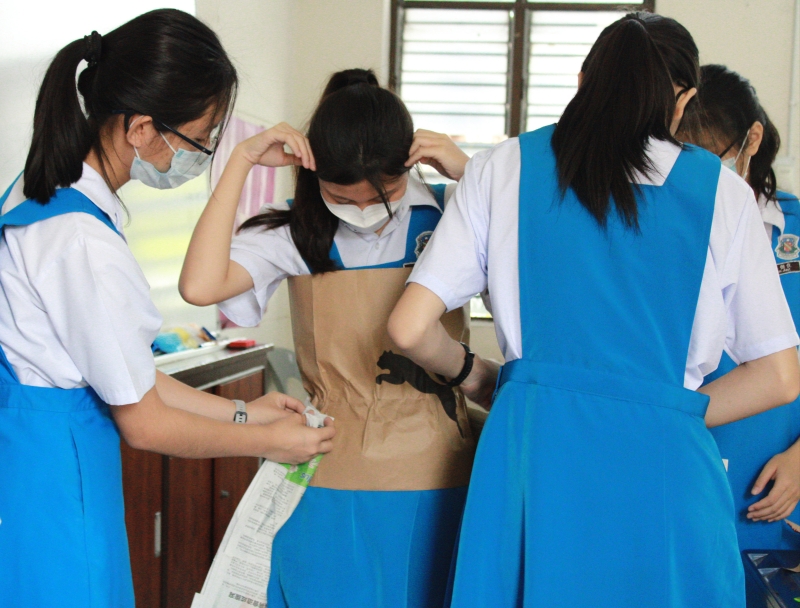 学生细心地为模特儿穿上服装。